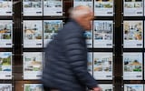 A pedestrian passes an estate agents window advertising properties