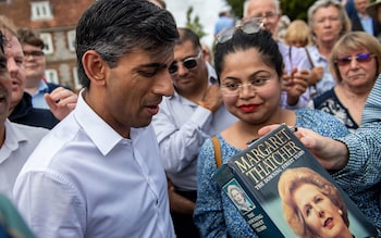 Rishi Sunak is handed a copy of former prime minister Margaret Thatcher's book to sign at an event at Manor Farm, in Ropley near Winchester, Hampshire