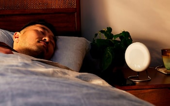 A man sleeps next to his bedside table