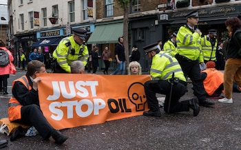 Police officers speak to Just Stop Oil supporters blocking the road outside Spitalfields Market in East London
