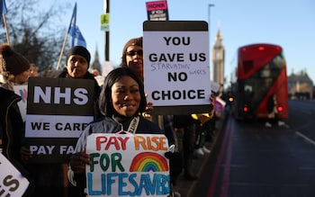 Demonstrators hold placards on a picket line  outside St Thomas' Hospital in London