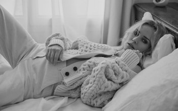 Diane Kruger in chunky cardigan lying across the bed